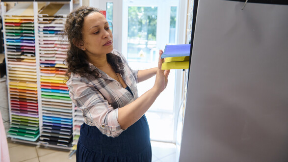 Schwangere Mitarbeiterin einer Papeterie räumt Regale ein