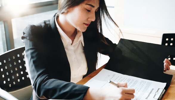 Junge Frau unterschreibt Arbeitsvertrag