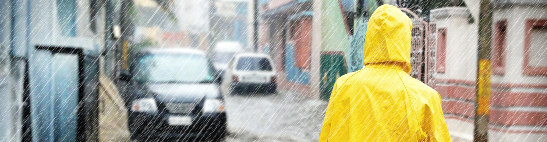 Mann mit Regenschutz bei Hochwasser in der Stadt