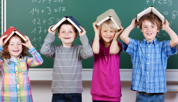 Kinder vor der Tafel mit Büchern am Kopf © fotolia/contrastwerkstatt, AK Stmk