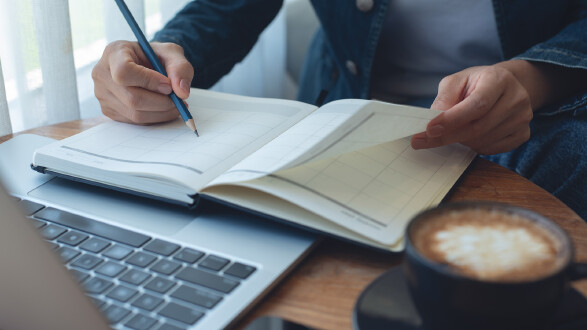 Person notiert mit Bleistift in einem Kalender.