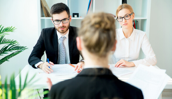 Mann und Frau sitzen einer Bewerberin für einen Job gegenüber