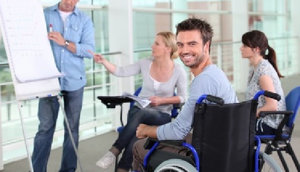 Junger Mann im Rollstuhl nimmt an einer Besprechung teil