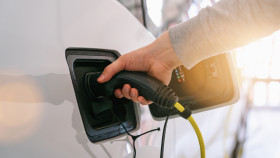 Ein Arm fürht einen Ladestecker in den Ladesanschluss eines elektrischen Fahrzeuges. © rcfotostock, stock.adobe.com