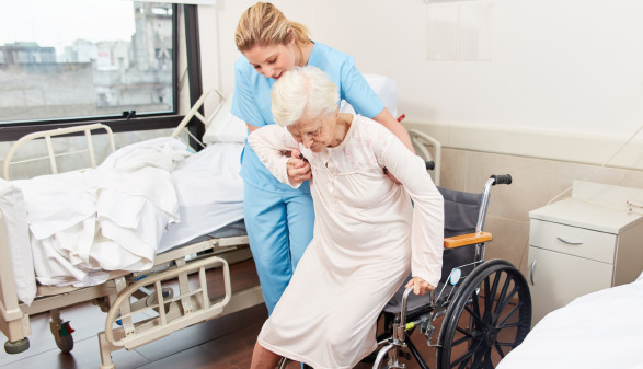 Pflegekraft hilft älteren Frau in den Rollstuhl © Robert Kneschke, stock.adobe.com