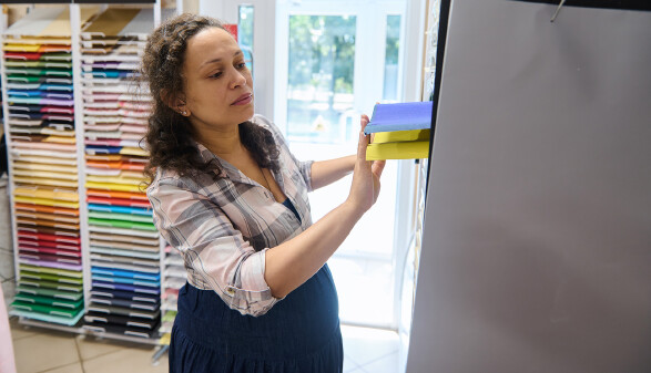 Schwangere Mitarbeiterin einer Papeterie räumt Regale ein