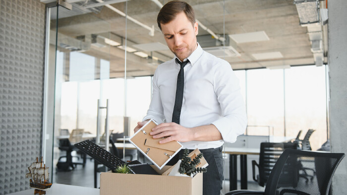 Mann räumt im Büro Dinge in einen Karton
