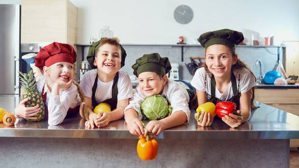 Vier Kinder in einer K&uuml;che mit Obst und Gem&uuml;se