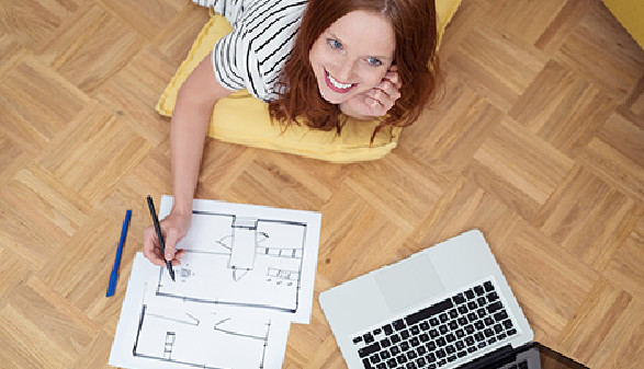 Lächelnde Frau zeichnet Skizze von Wohnung. © contrastwerkstatt, AK