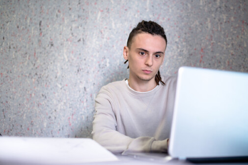 Junger Mann arbeitet konzentriert am Laptop