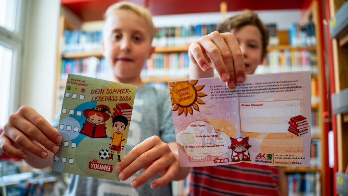 Zwei Kinder halten den Sommer-Lesepass der Arbeiterkammer Steiermark 
