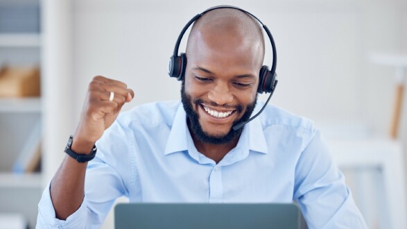 Callcenter-Agent mit Headset l&auml;chelt w&auml;hrend der Arbeit