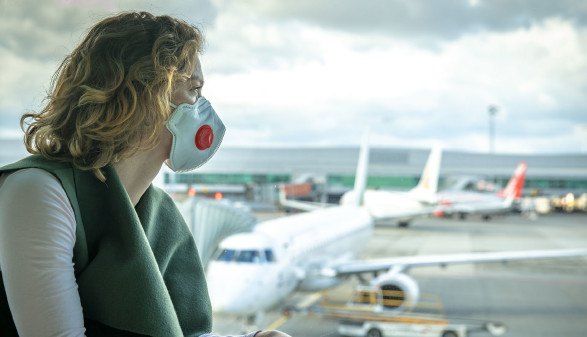Frau mit Mundschutz blickt auf Flughafen © edojob , stock.adobe.com