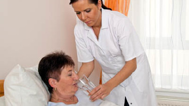 Pflege daheim - Krankenpflegerin hilft Ihrer Patientin beim Trinken!